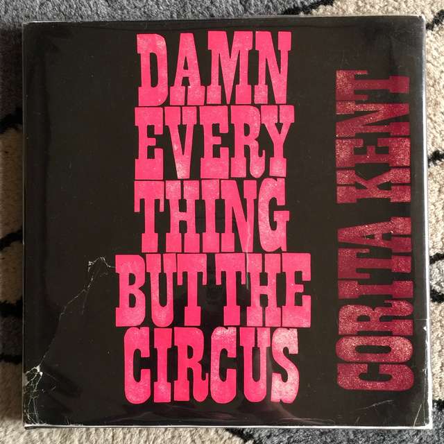The cover of Damn Everything But the Circus, with bold pink text for the title of black background