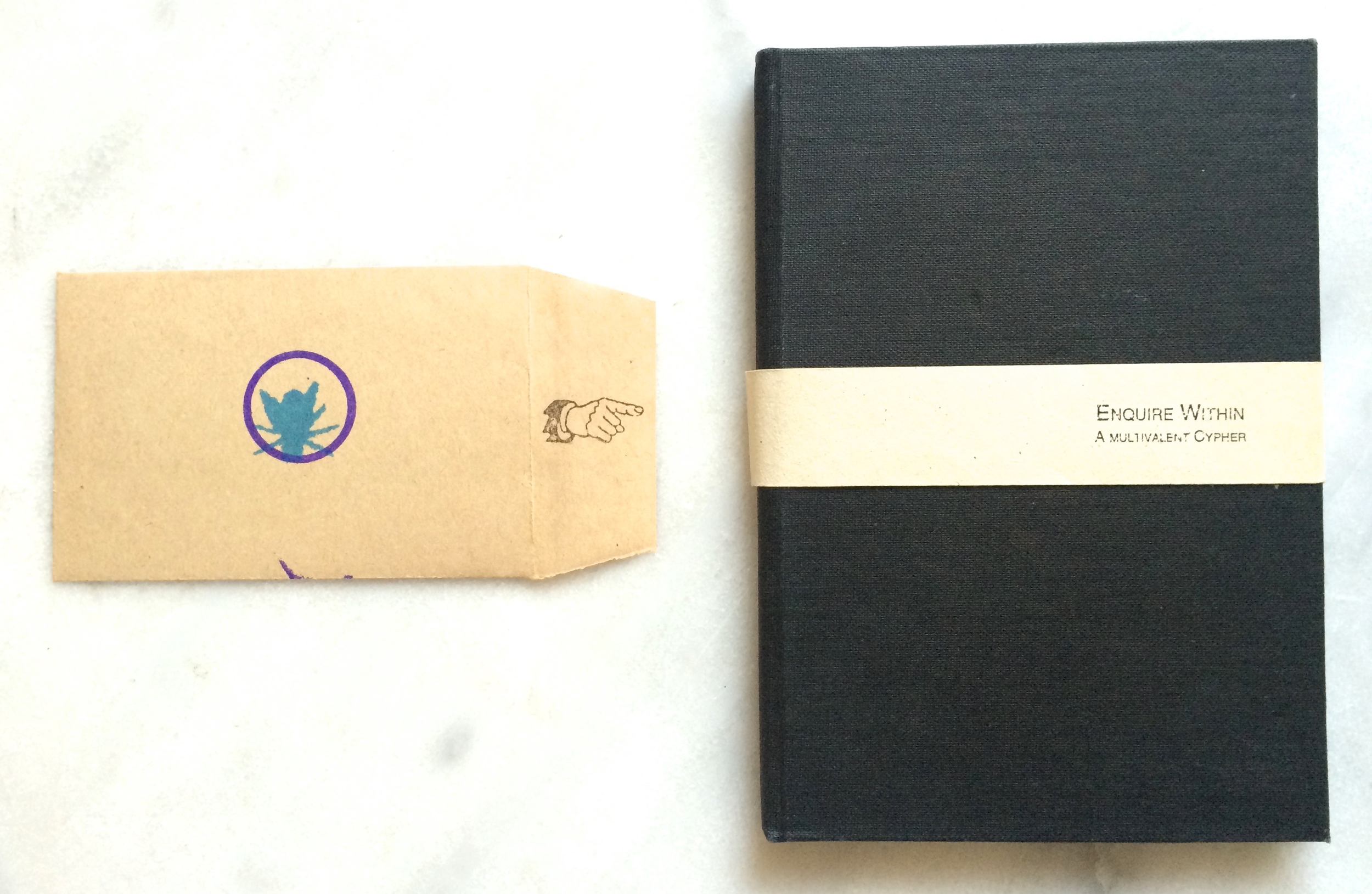 A black book next to a small envelope with a hand and fly rubber stamped on it