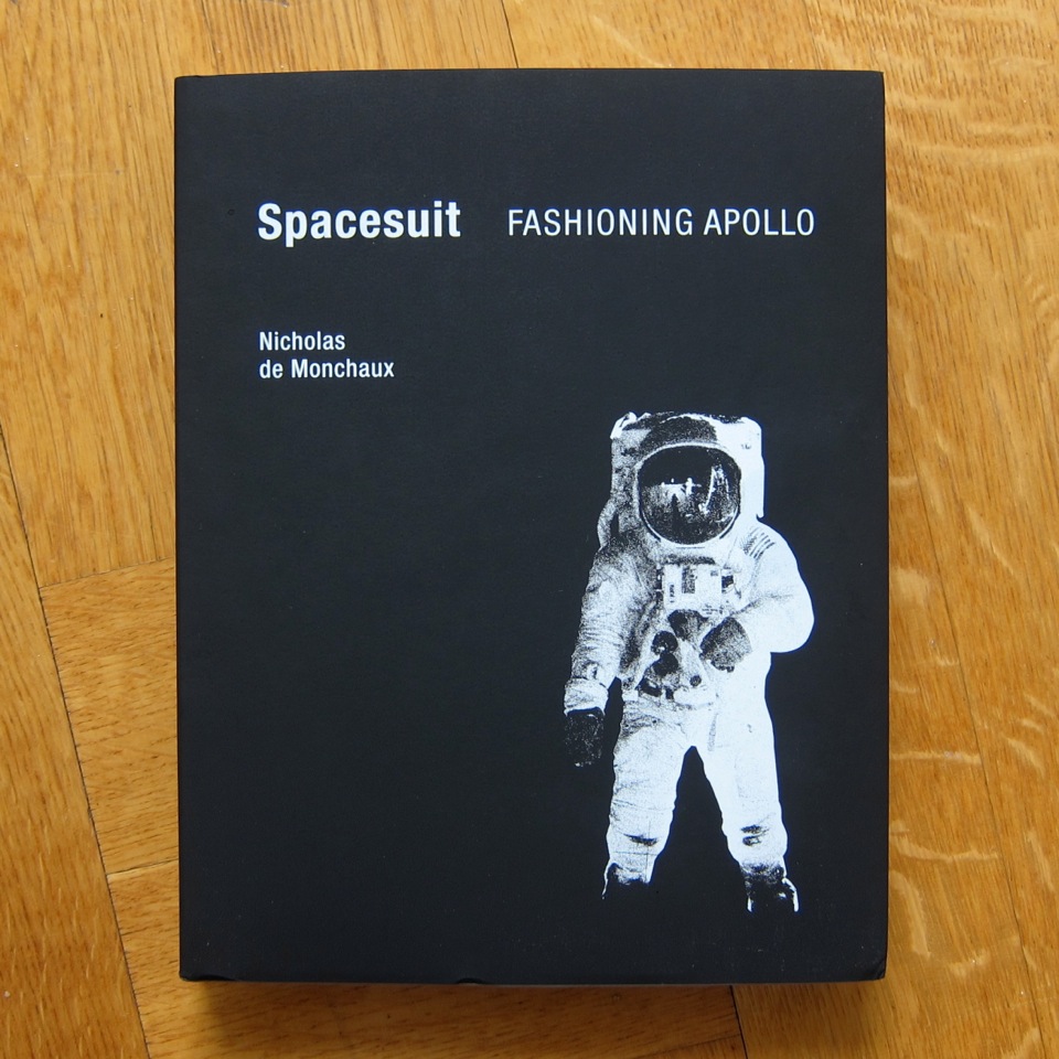 The book Spacesuit, with stark black cover and image of an astronaut in a space suit