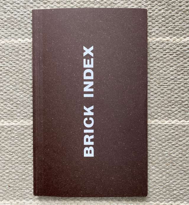 The cover of a book. The title, Brick Index, is printed vertically in bold white text against a dark brick red background.