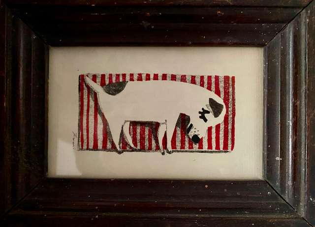 a framed illustration of a black and white dog laying on a red and white striped mat